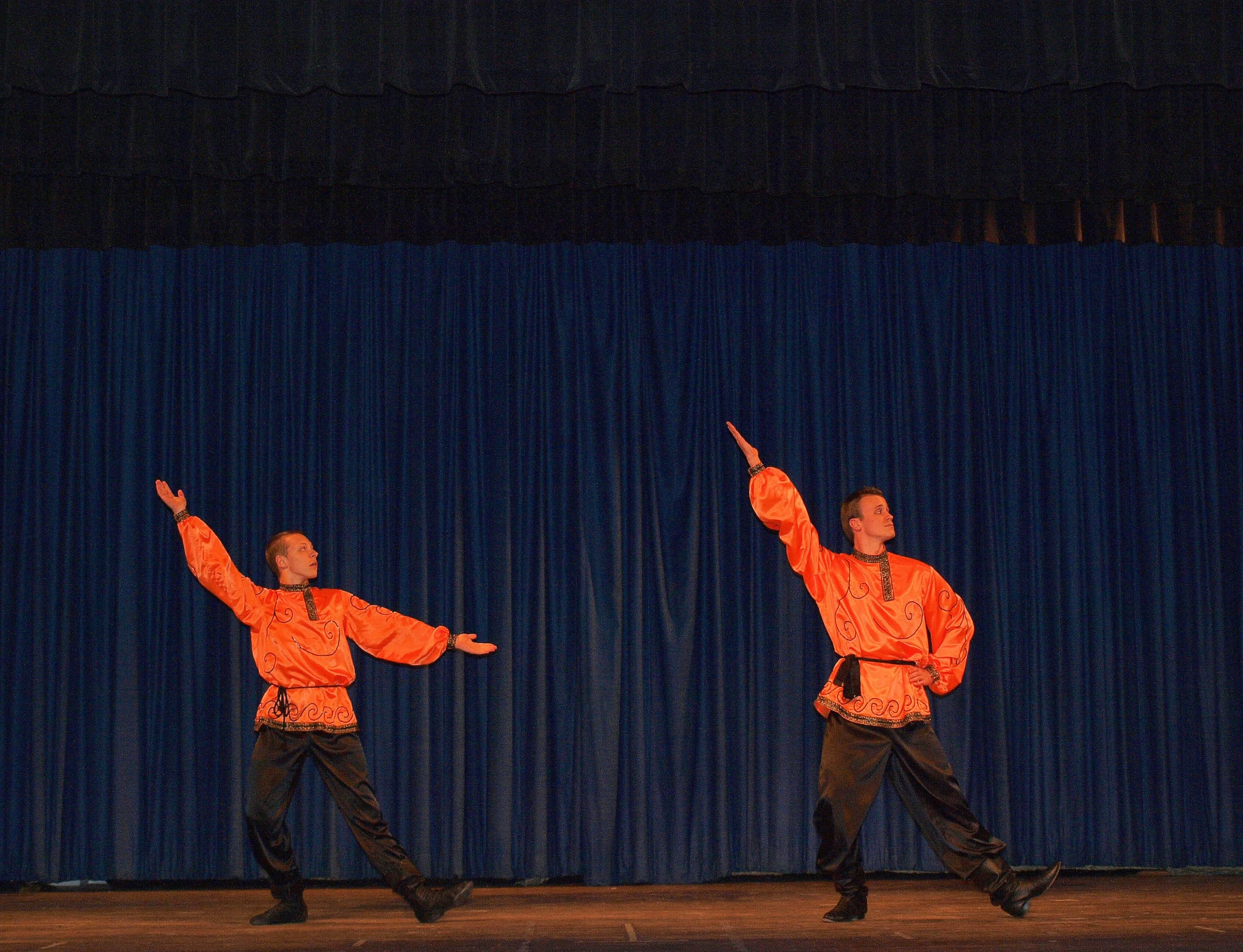 two people performing an acrobatic stunt in front of a curtain