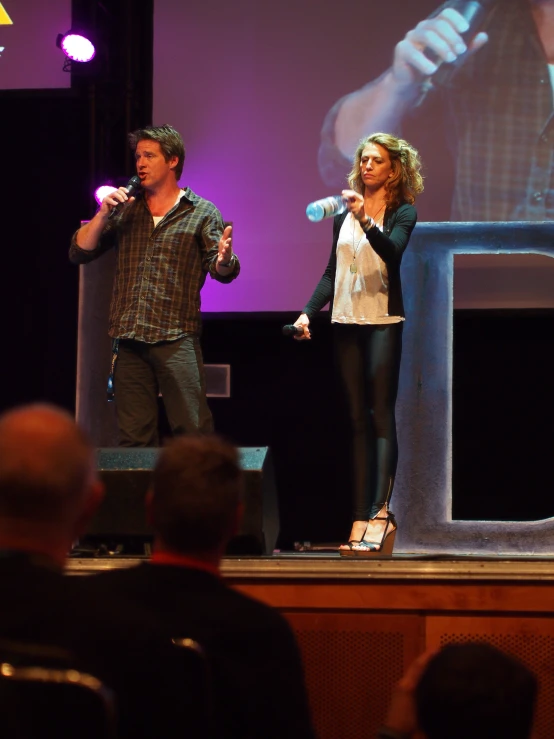 a man standing next to a woman on top of a stage