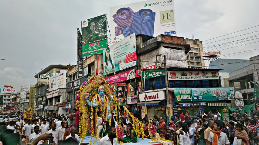 many people are walking around on the street with cars and tall buildings