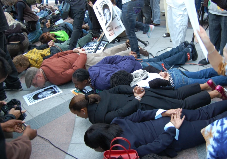 some people laying on the ground near some people using cellphones