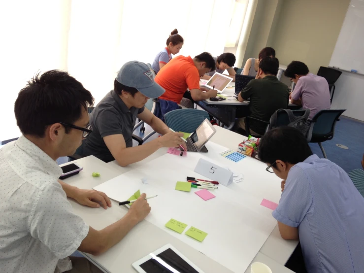 people sit at tables with notepapers and computers