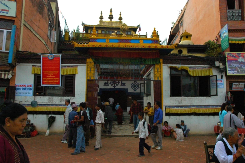 people gathered in the streets near a yellow and blue shrine