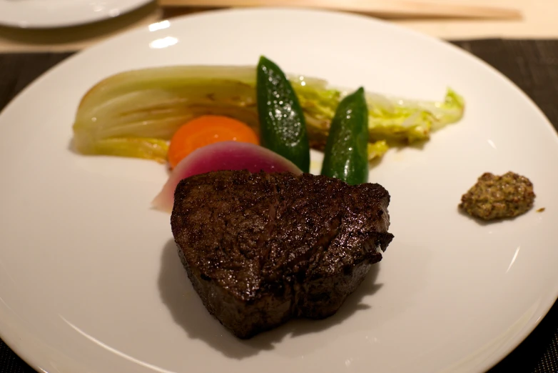 steak with pickles, carrots and an asparagus on a white plate