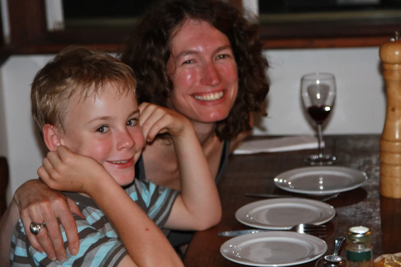 a mother and son smiling at the camera while sitting at a table