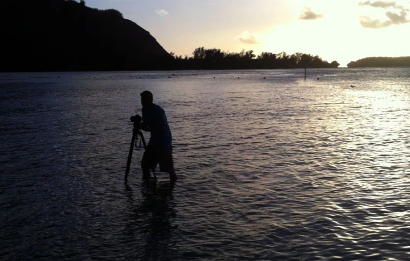 a man standing in a large body of water holding a bike