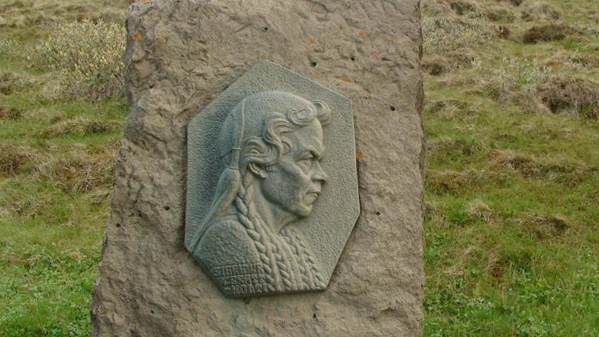 a stone carving of a head with a hat is sitting on the ground