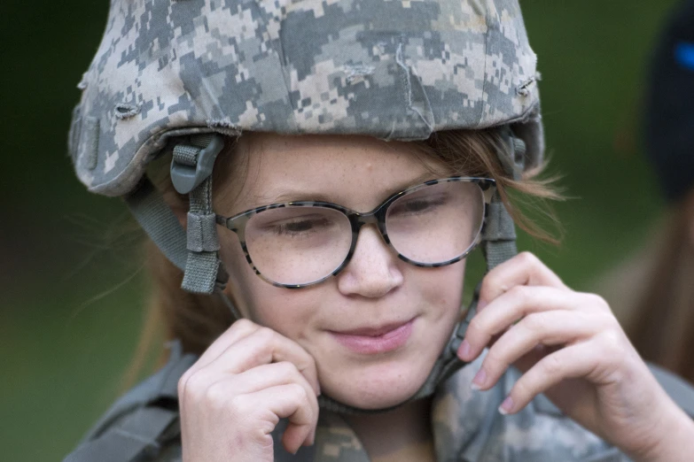 a woman in glasses wearing a helmet while looking down