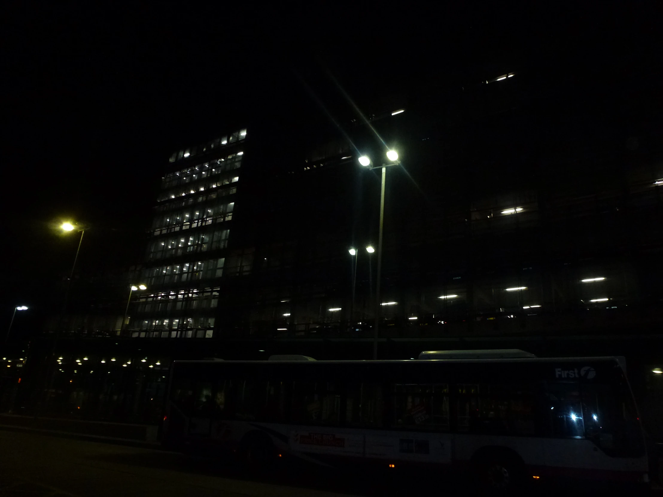 a city bus sits at night in front of a building