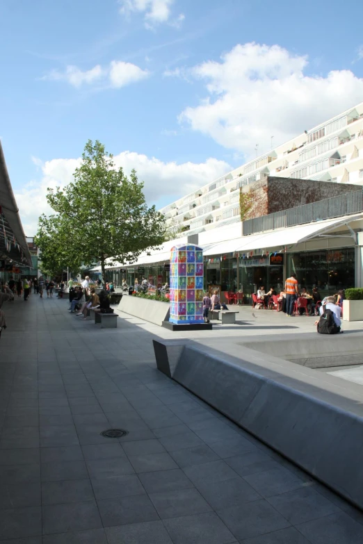 a sidewalk is lined with benches and people