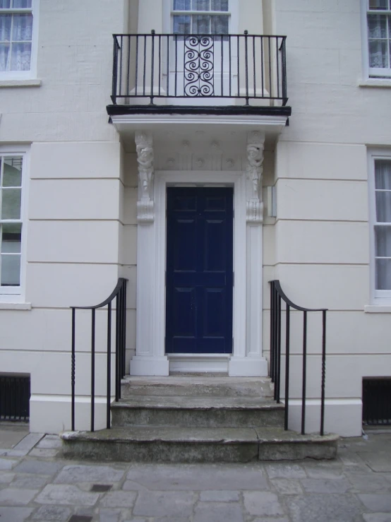 an apartment with a blue door, two balconies and wrought iron railings