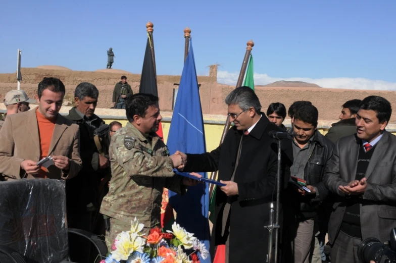 the man stands in front of flags with his hands raised