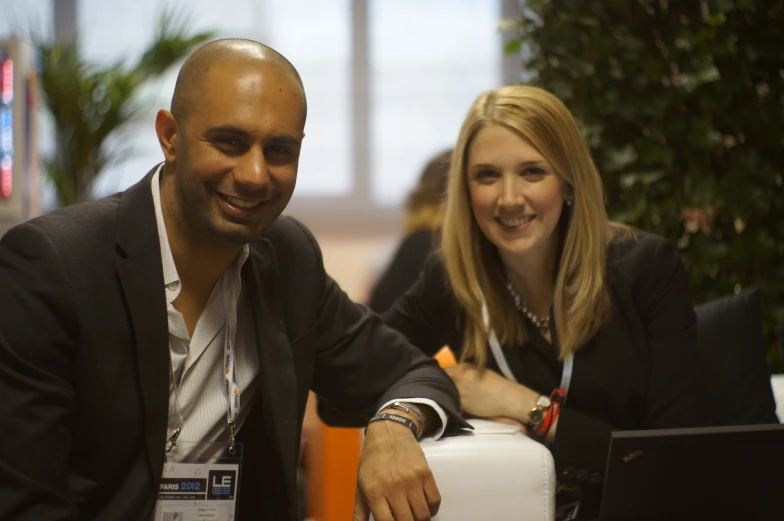 an attractive woman sitting next to a man at a desk