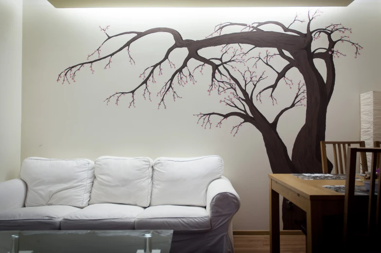 a tree painted on the wall above the sofa