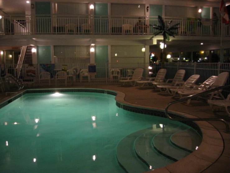 an indoor pool is surrounded by chaise lounges