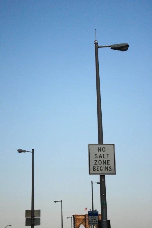 a street lamp next to a sign that says no salt begins