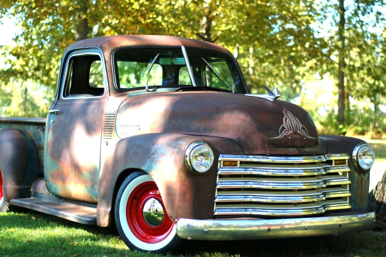 an antique truck is parked in the grass