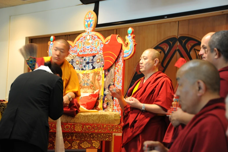 several men in chinese clothes stand in front of the red altar