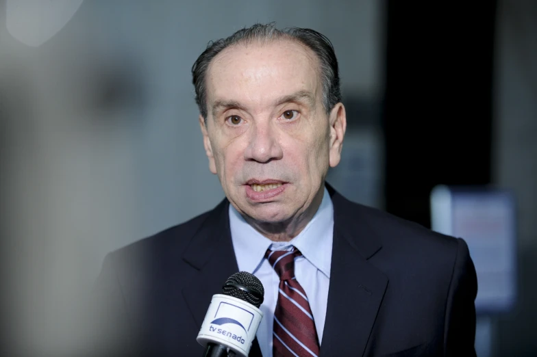 a man speaking into a microphone wearing a suit