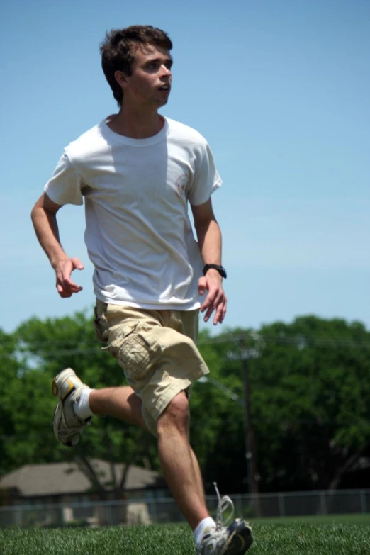 a man in shorts and t - shirt running on the grass