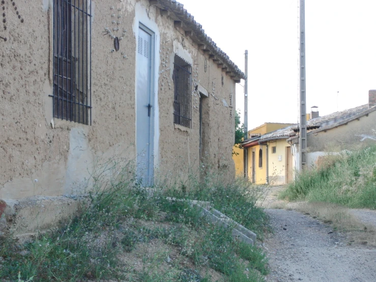 a building on a dirt path next to some tall buildings