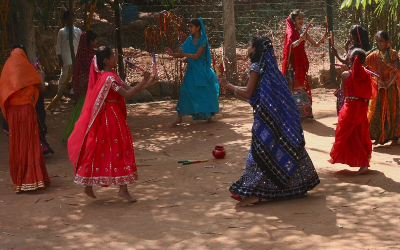 a group of women in brightly colored saris dancing together