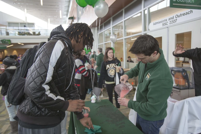 young men are having drinks from cups in an airport