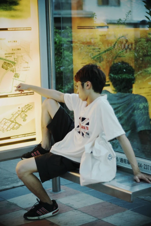 a young man sitting on a bench looking out a window