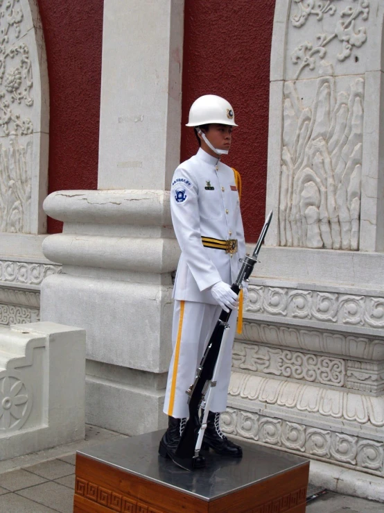 a military man in uniform standing by a statue