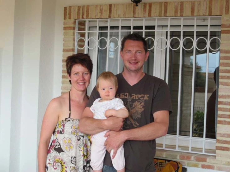 a man, woman and baby are standing in front of a window