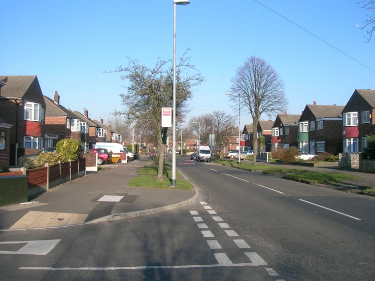 an empty city street with houses and lots of trees