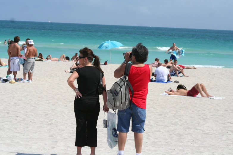 two people in sunglasses and black shirt are on the beach