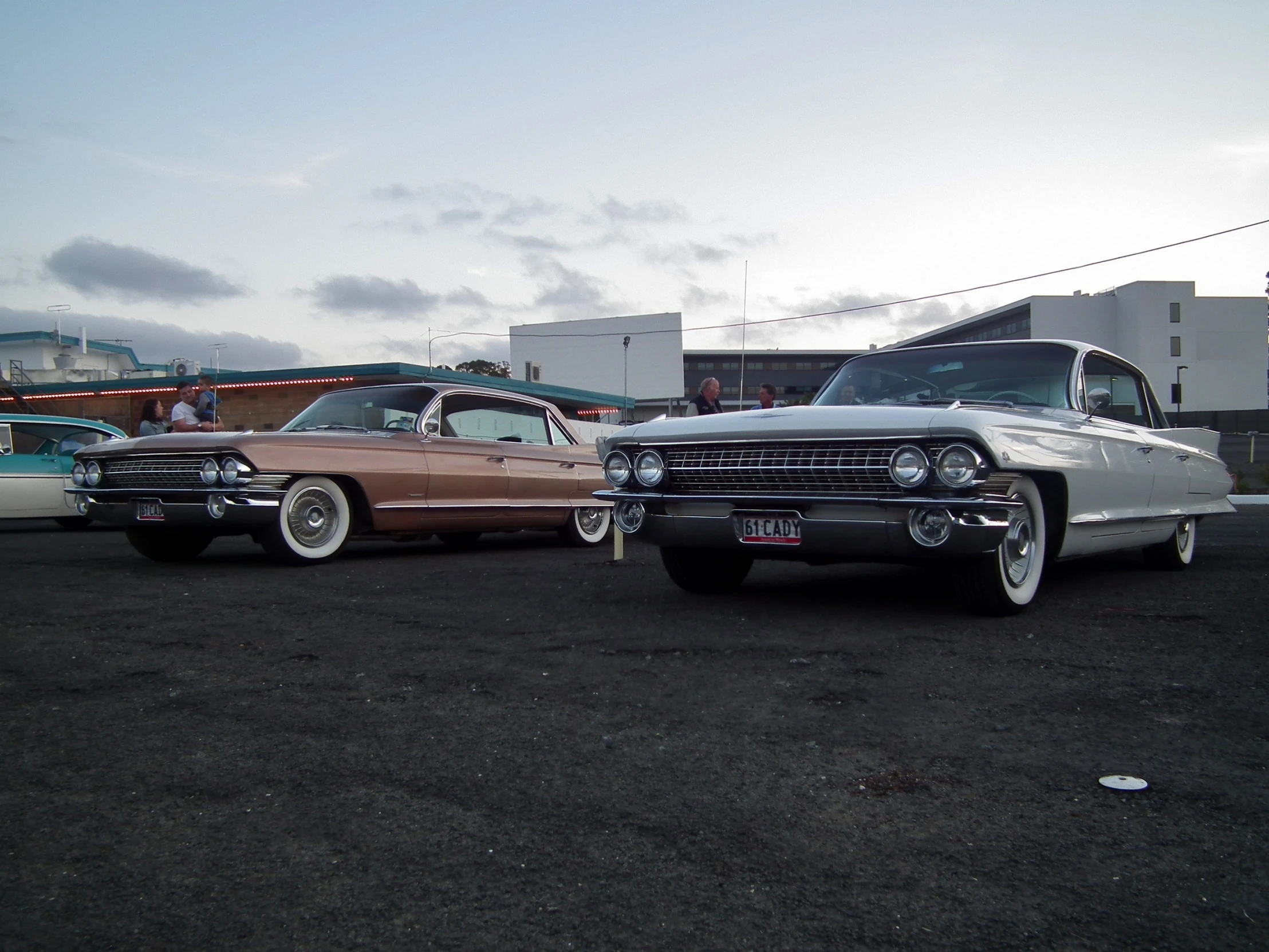 two classic cars sitting parked in a lot near other cars