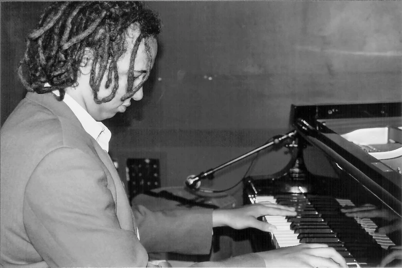 a woman in suit playing piano in front of a microphone