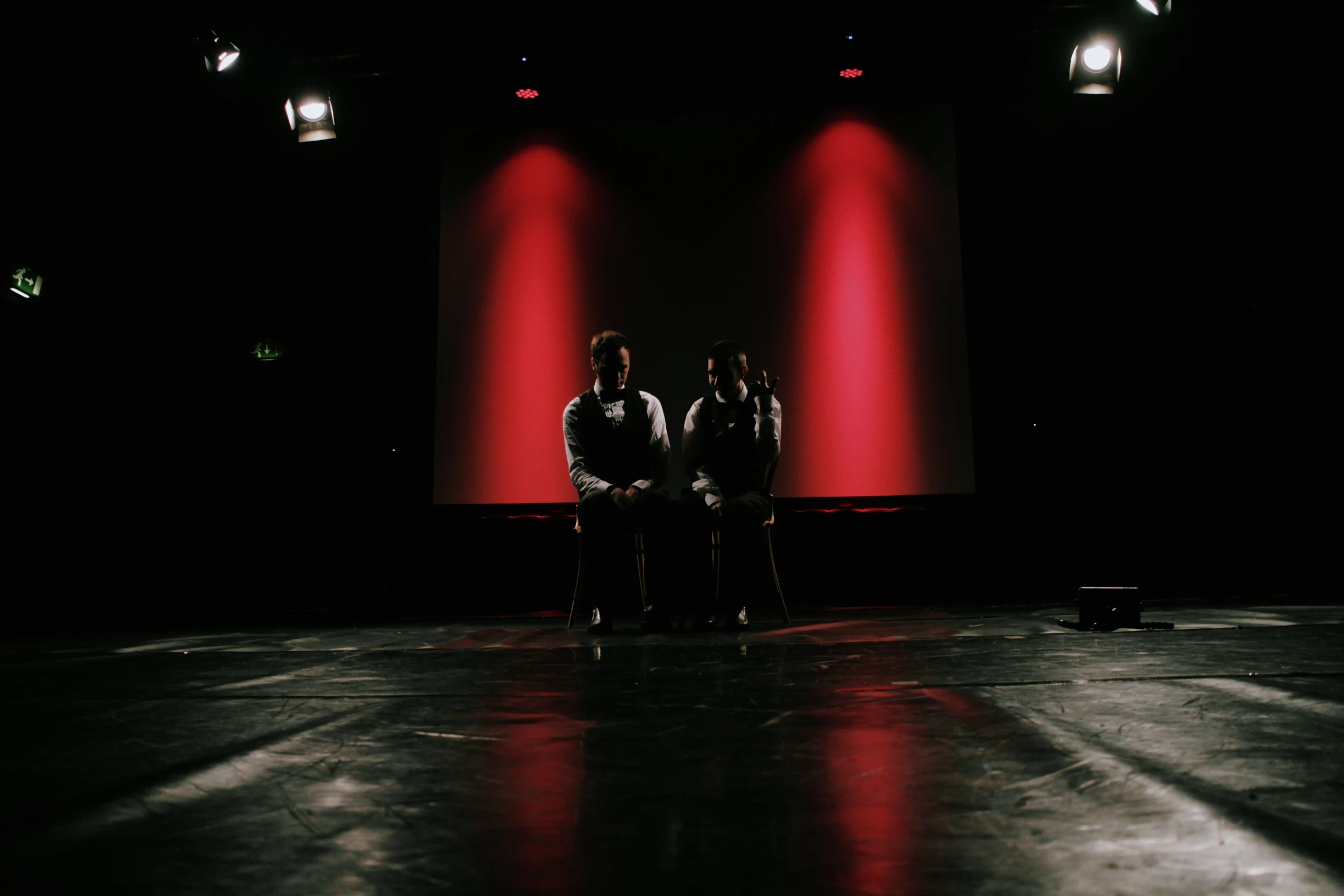 three people standing in a dark room next to red lights