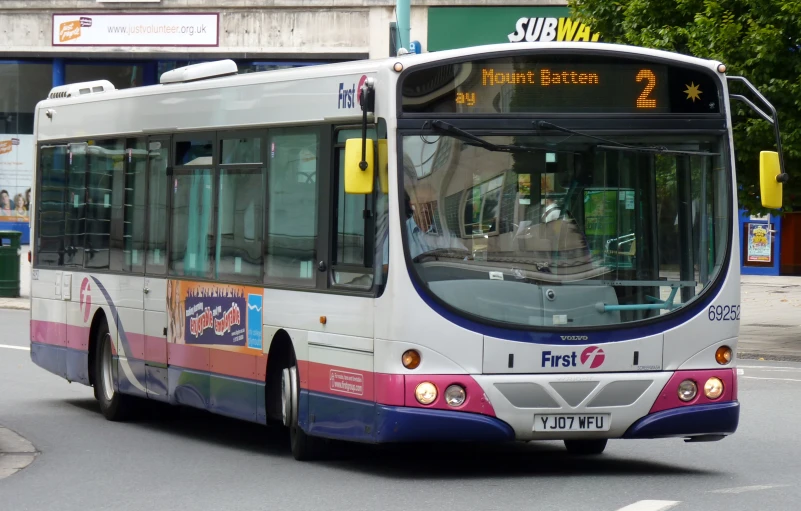 a white bus driving down a city street