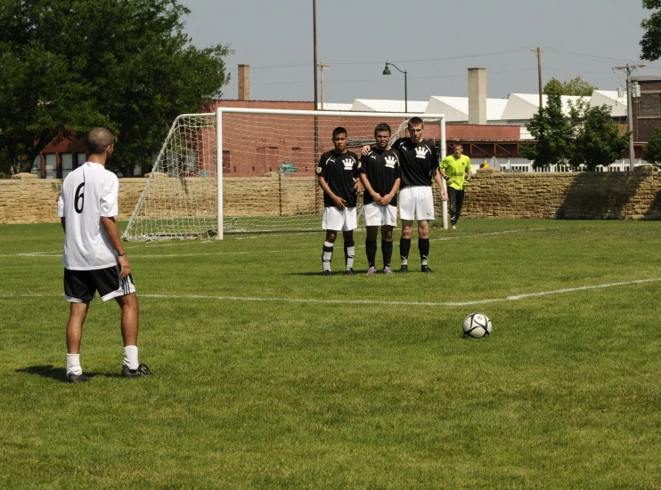 some people are standing around in the grass by a soccer ball