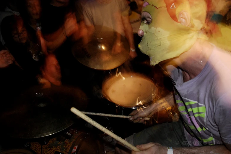 man playing drums with a group of people watching