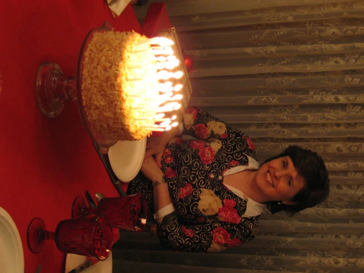 a woman standing behind a large cake with lit candles