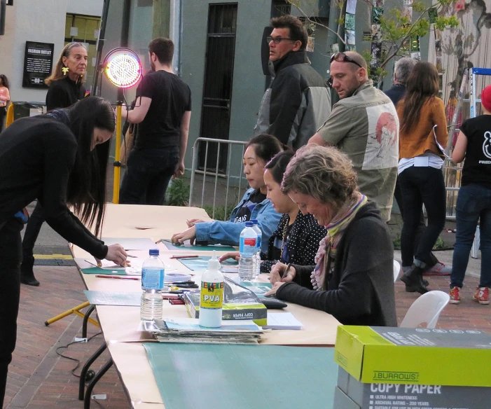 a woman handing food to other people at an outdoor table