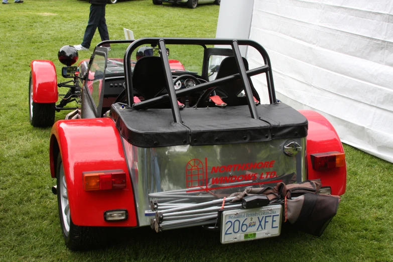 a red and black vehicle on grass with people