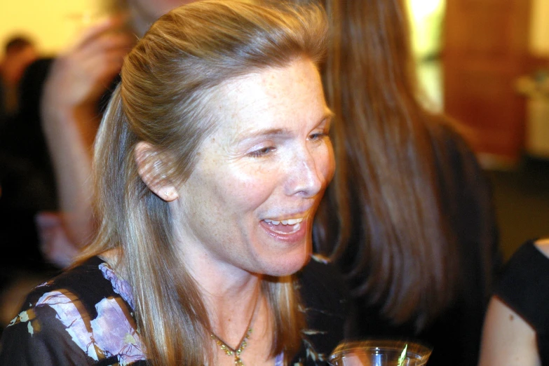 a woman smiles while holding a wine glass