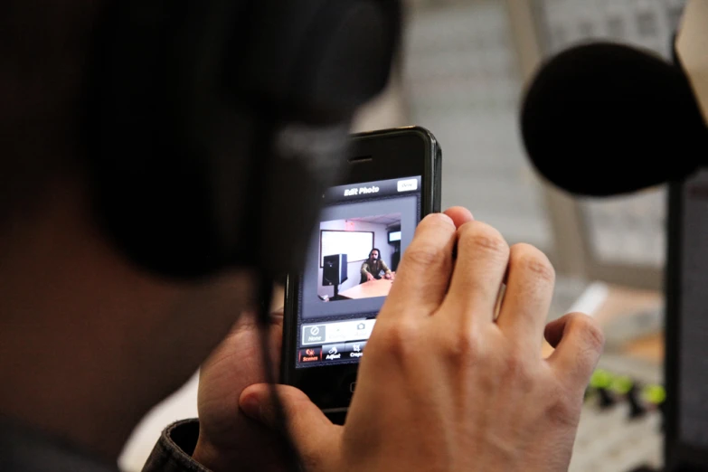 the man is recording the live television show on his cell phone