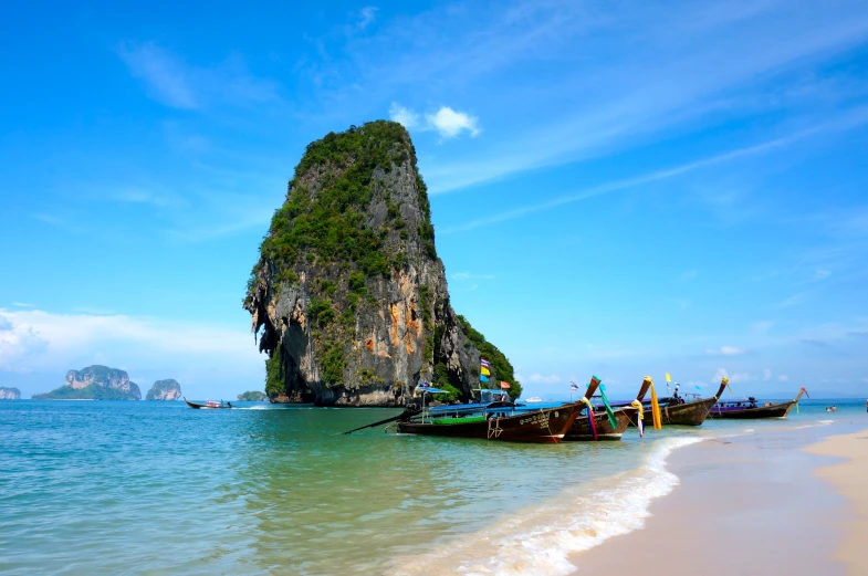 a group of long boats in a body of water next to beach