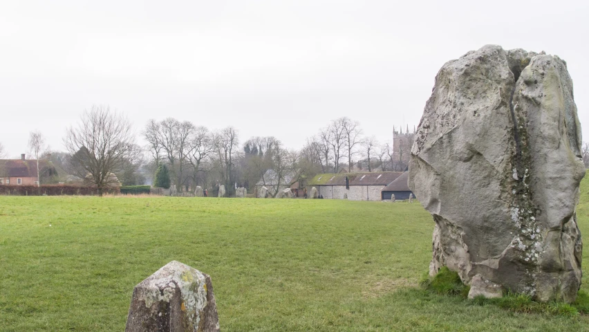 a stone standing on top of a grass covered field