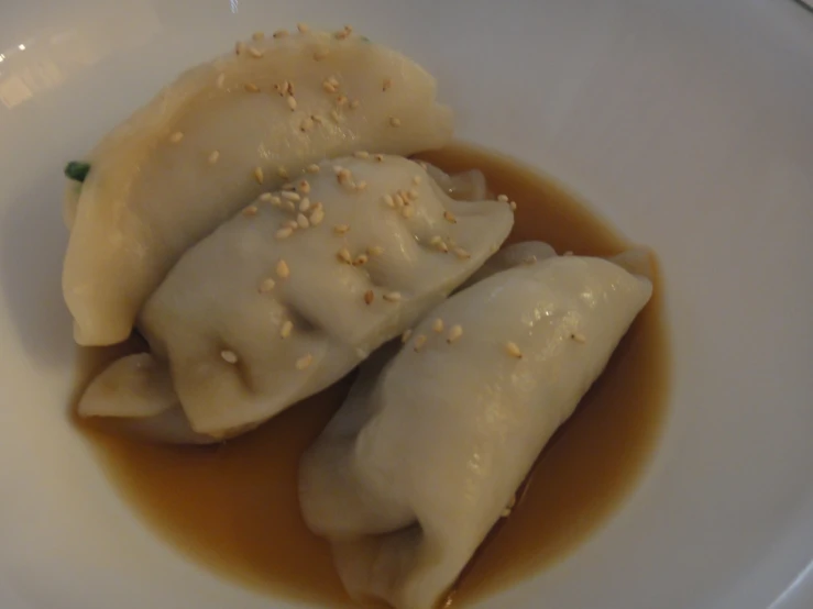 two dumplings with sauce on top of a white plate