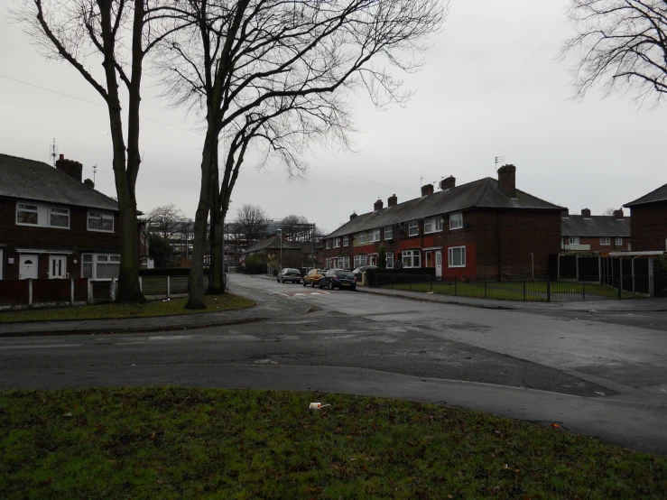 a city street on a rainy day with some trees and houses