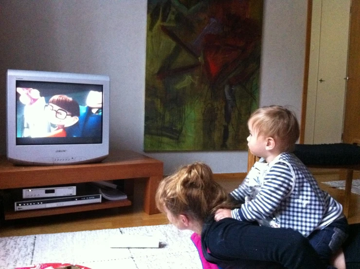 a little boy watching tv with his parents