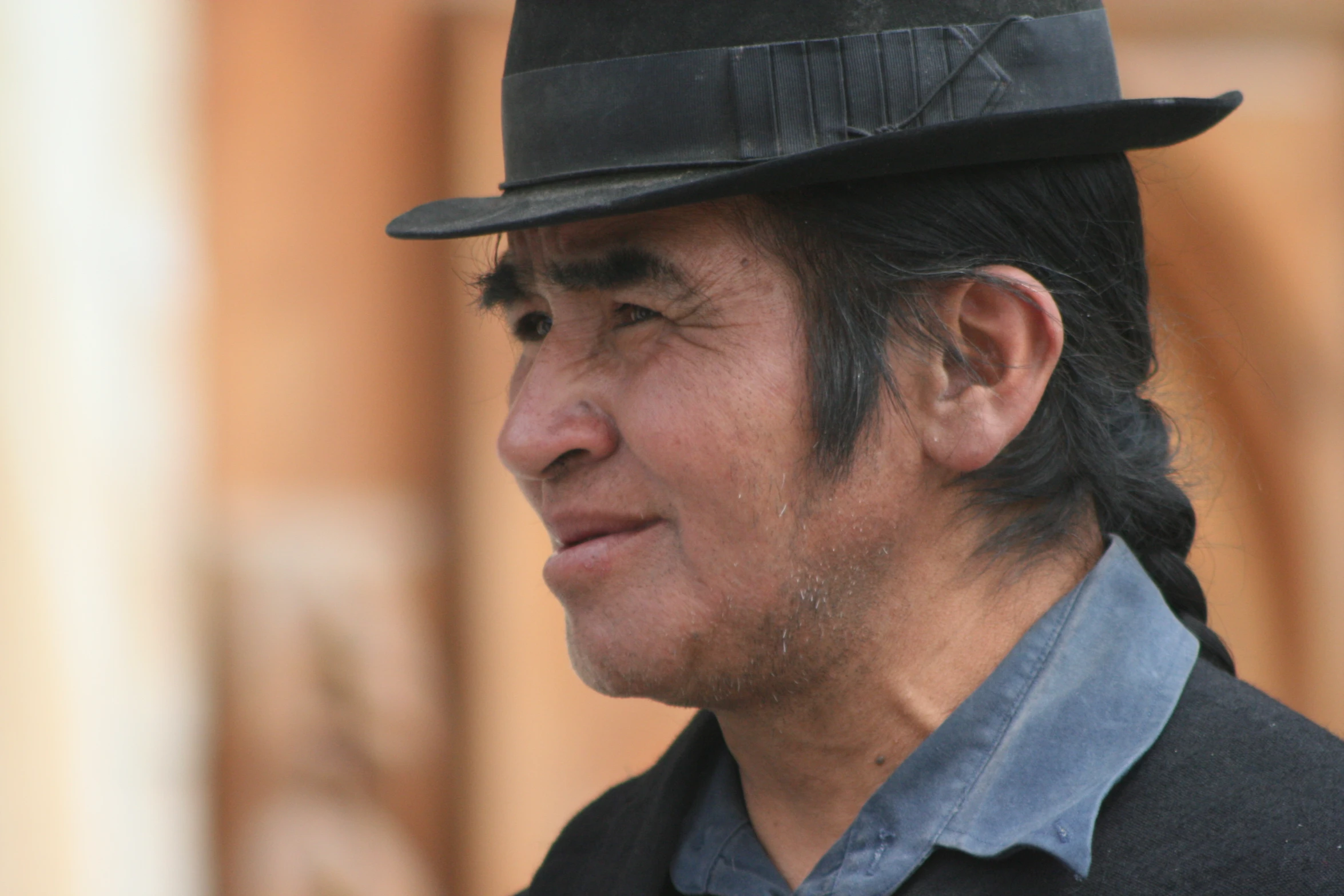 man in hat wearing dress clothes standing next to brown building