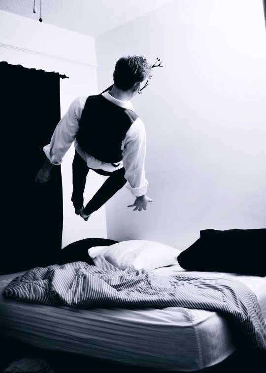 a man on a skateboard doing tricks over a bed