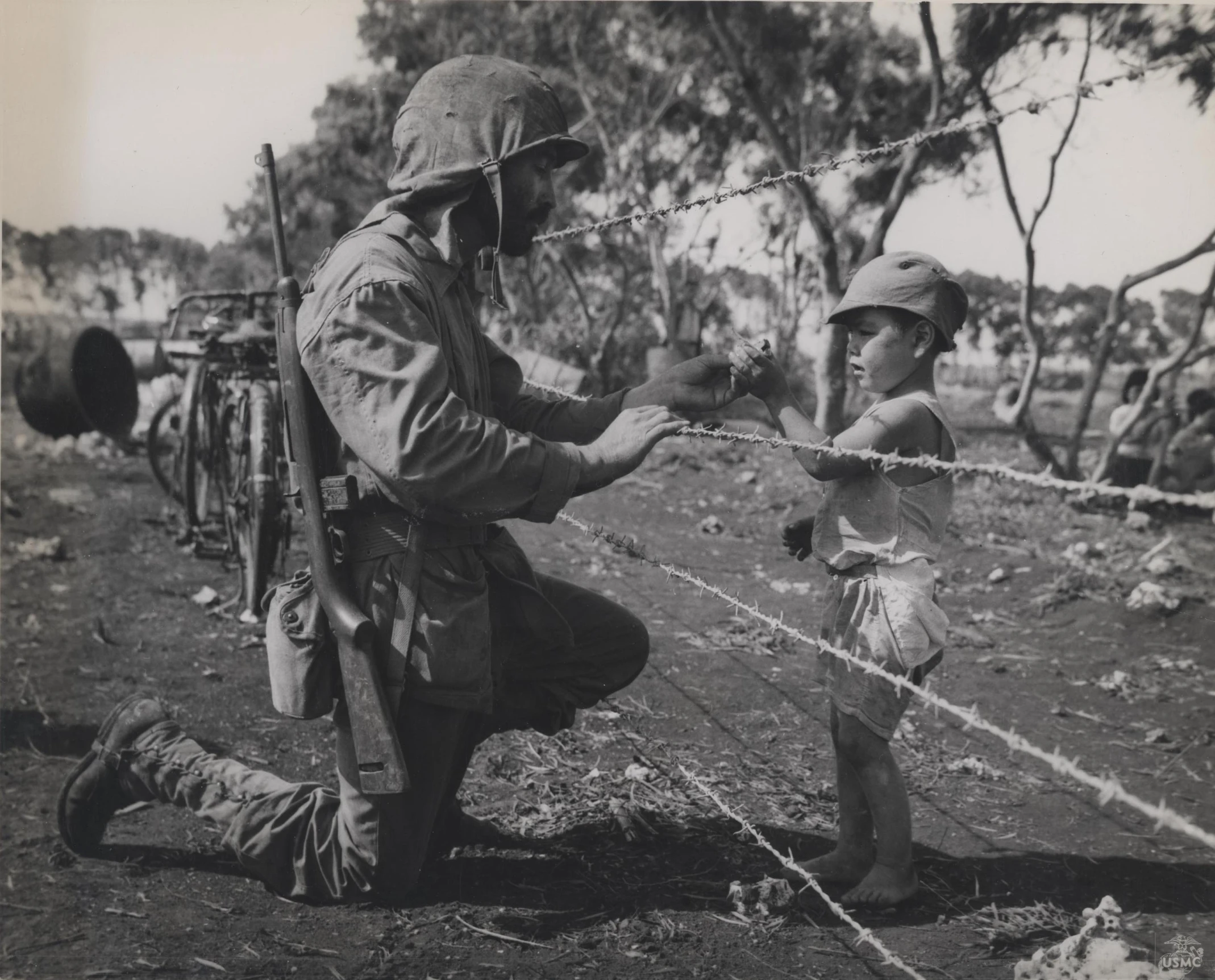 a man and little girl are looking at soing through barbed wire